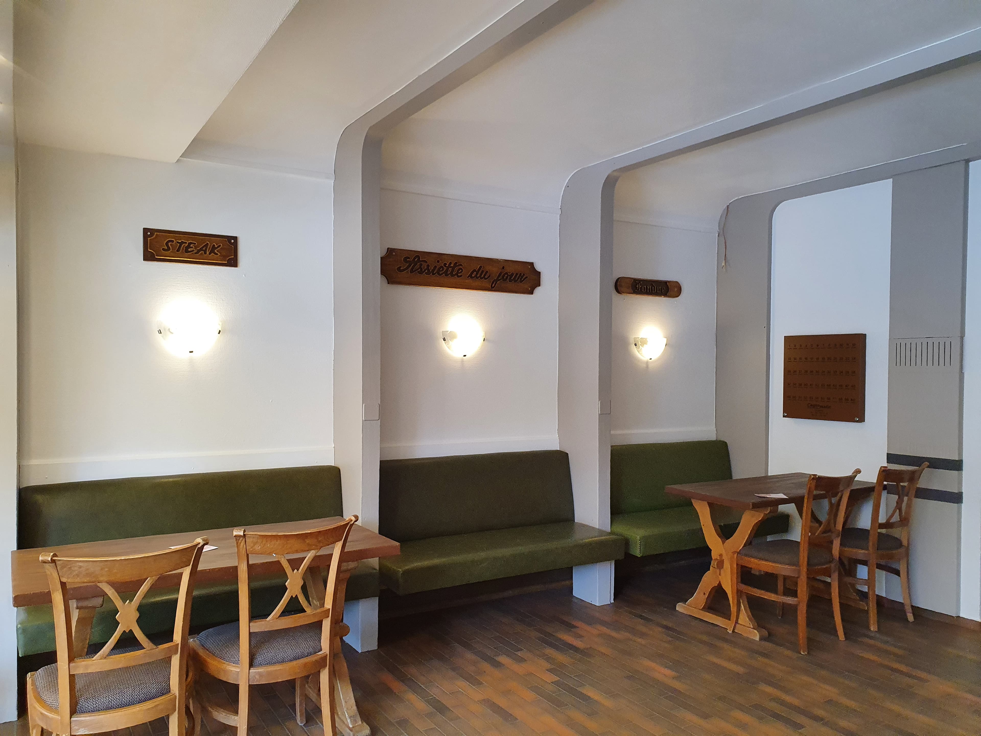 La salle du Bistrot du Parc, banquettes vert sapin et tables en bois