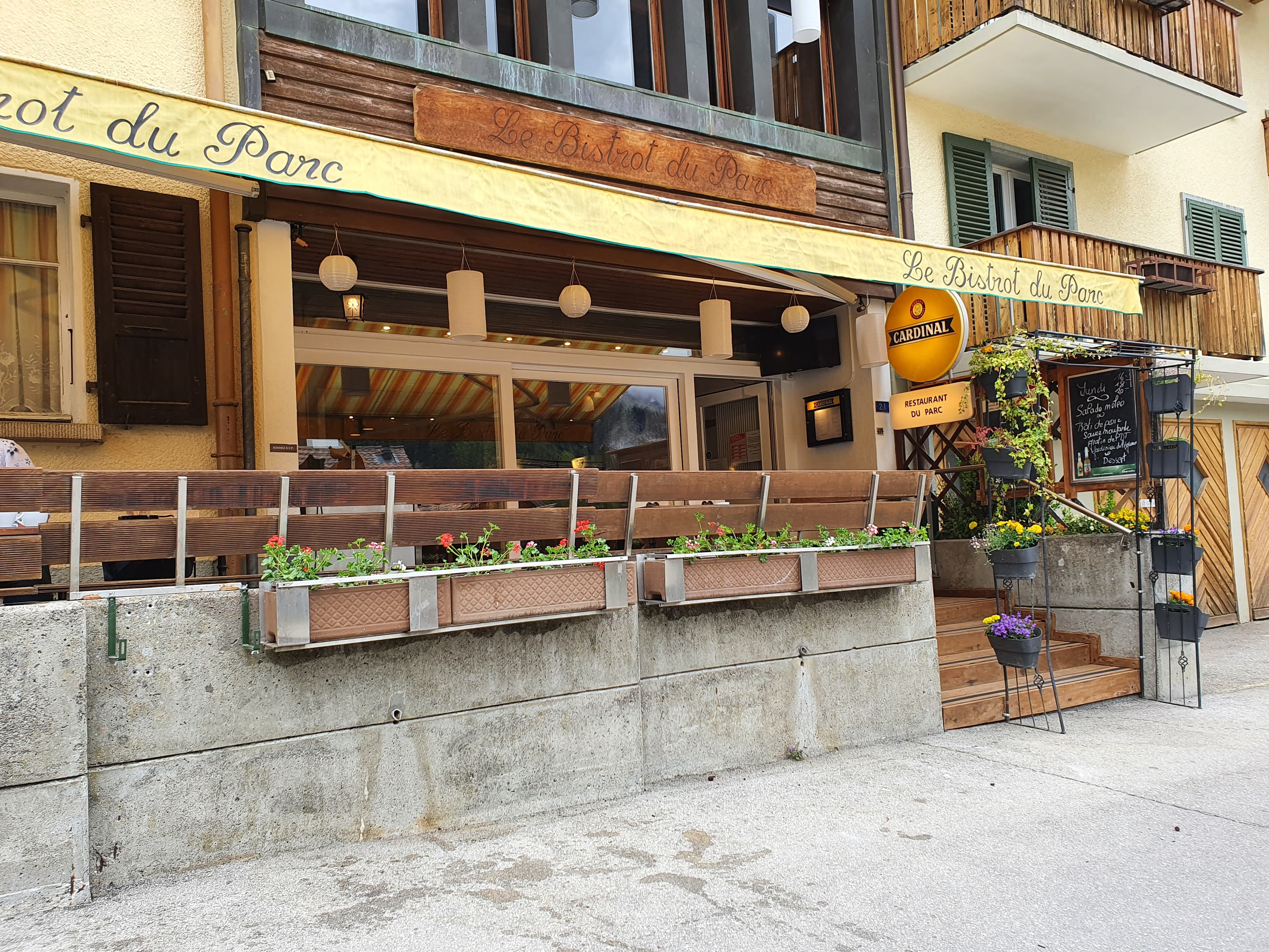 La façade chalet et la terrasse fleurie du Bistrot du Parc à Charmey